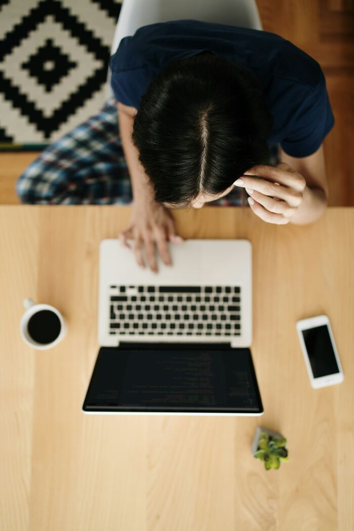 Persona preocupada frente a laptop, rodeada de objetos, simbolizando experiencias online aterradoras.