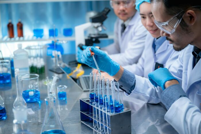 Grupo de científicos en laboratorio realizando experimentos con tubos de ensayo, mostrando momentos de corrección fallida.