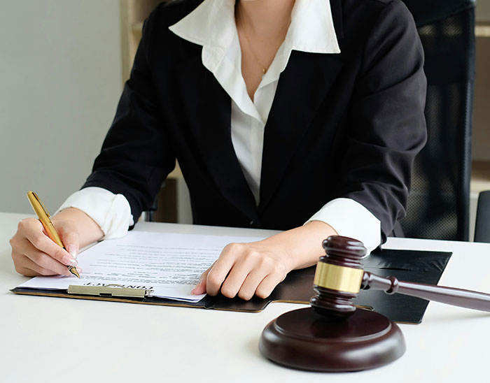 Abogada en oficina revisando documentos legales con mazo de juez, representando abogados y clientes en casos legales.
