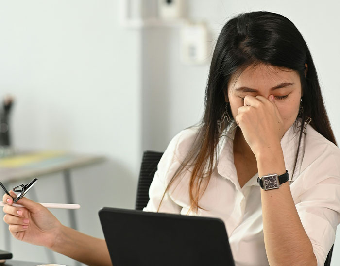 Mujer pensativa en oficina mostrando frustración, ilustrando abogados y las estupideces que hicieron sus clientes.