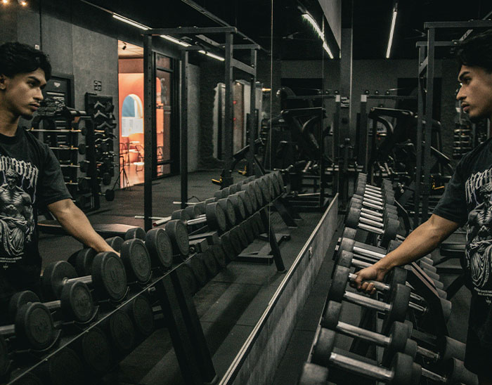 Joven en gimnasio junto a mancuernas, ilustrando historias de abogados sobre clientes y sus errores comunes.