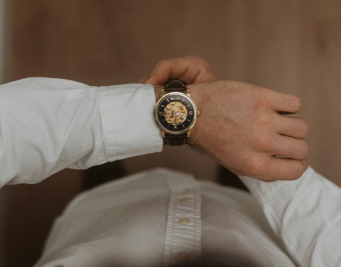 Hombre con camisa blanca revisando reloj de pulsera lujoso en contexto relacionado con abogados y clientes.