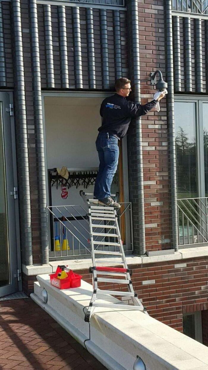 Hombre en escalera realizando mantenimiento en lámpara exterior, ilustrando riesgos que influyen en la longevidad entre mujeres y hombres.