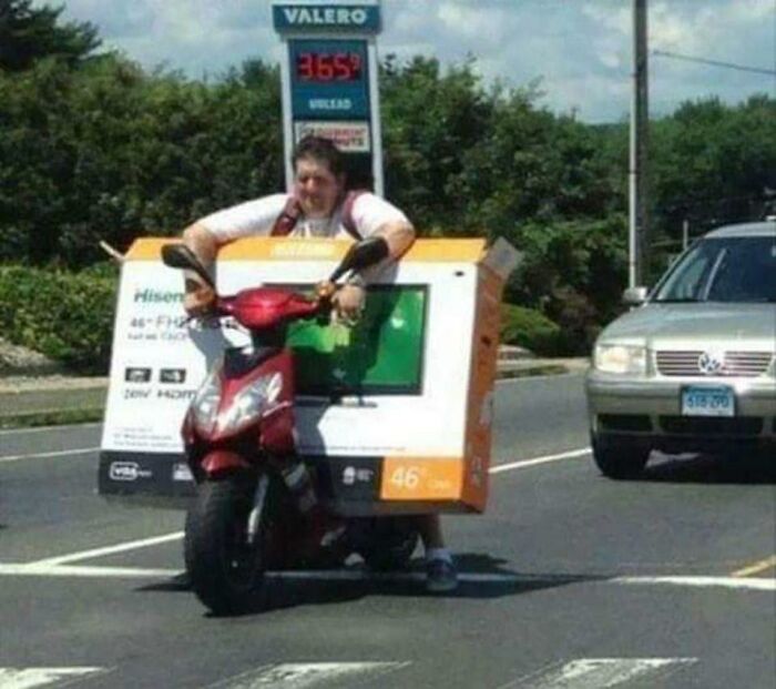 Hombre en moto cargando una pantalla grande, imagen relacionada con razones por las que las mujeres viven más que los hombres.