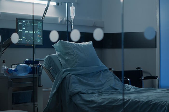 Habitación de hospital vacía con cama y monitor, ilustrando momentos clave de trabajadores sanitarios en emergencias.