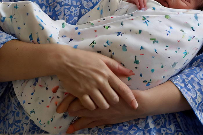 Trabajadora sanitaria sosteniendo con cuidado a un bebé envuelto en manta blanca con detalles de colores pequeños.