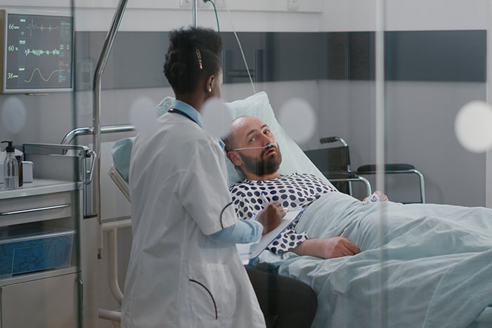 Trabajadora sanitaria atendiendo a un paciente hospitalizado en una habitación médica moderna y equipada.