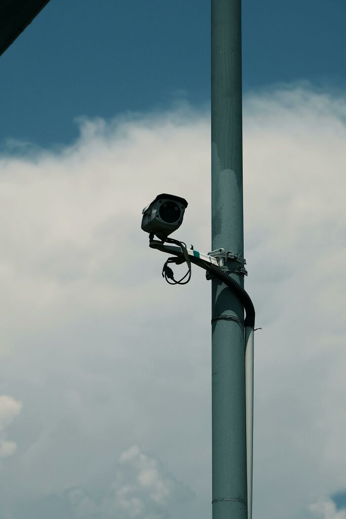 Cámara de seguridad instalada en poste gris vigilando el entorno, imagen que refleja experiencias online más aterradoras.