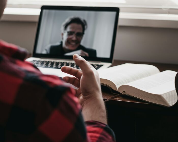 Persona en videollamada interactuando frente a un libro abierto, compartiendo experiencias online aterradoras.