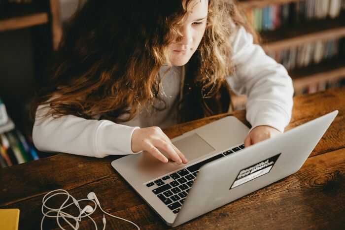 Niña con cabello rizado usando laptop y explorando experiencias online aterradoras en un entorno cómodo y hogareño.