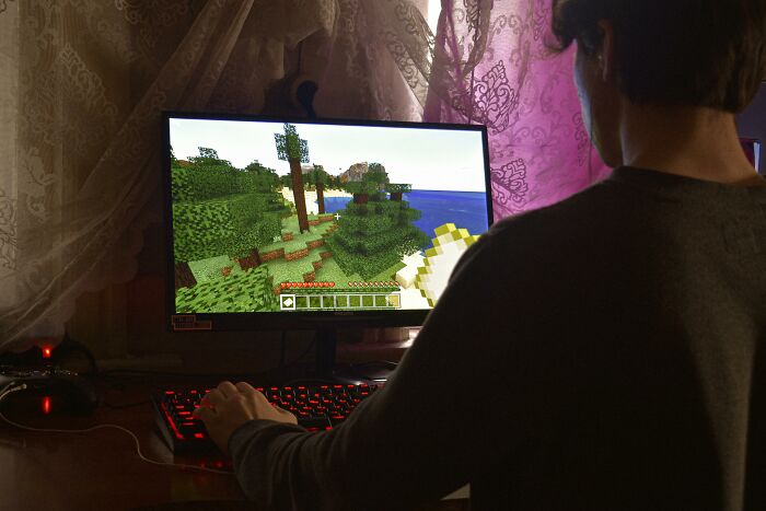 Persona jugando videojuegos online en un ambiente oscuro, representando experiencias online aterradoras compartidas.