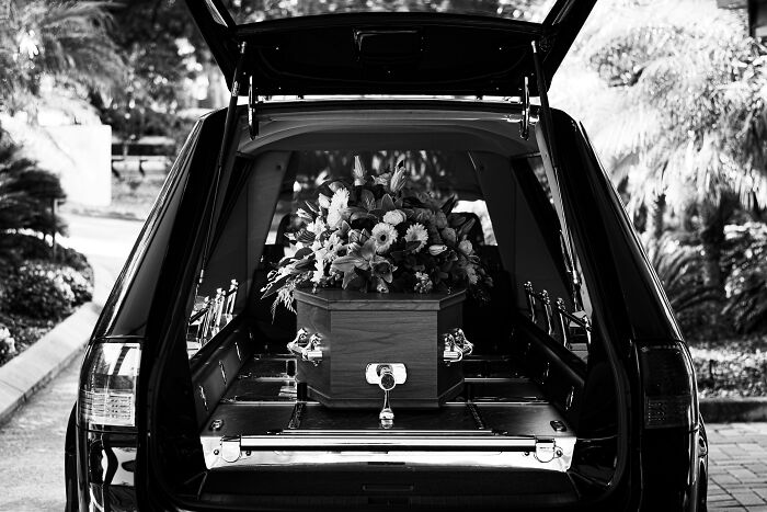 Ataúd con flores dentro de un vehículo fúnebre, ilustrando experiencias online más aterradoras compartidas por personas.