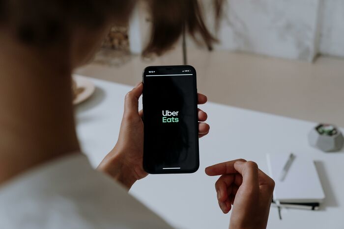 Mujer usando Uber Eats en su teléfono móvil aplicando consejos útiles para mujeres que viven solas.