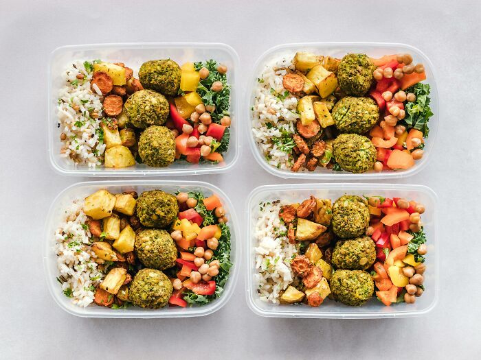 Cuatro recipientes con comida saludable y variada, ideal para mujeres que viven solas y buscan consejos prácticos.