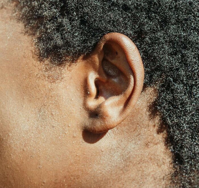 Close-up de oreja y piel de persona con genes únicos en textura y características naturales del cabello afro.