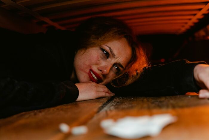 Mujer con expresión aterrorizada escuchando conversaciones privadas terroríficas en un ambiente oscuro y tenso.