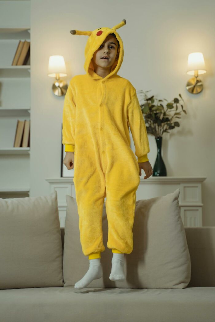 Niño vestido con disfraz amarillo saltando en sofá en casa, reflejando momentos de corrección fallida y confusión.