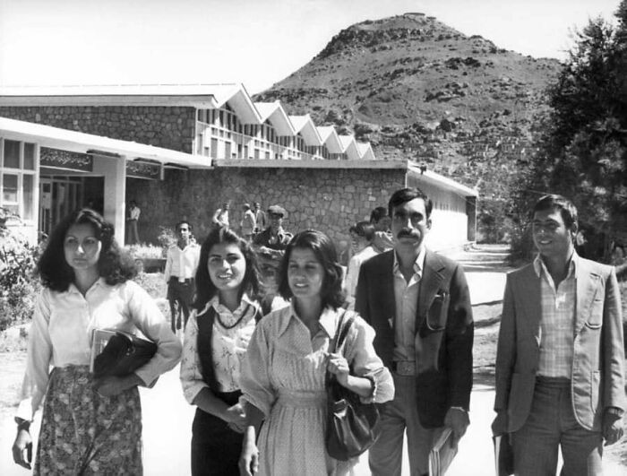 Grupo de personas caminando frente a edificio de piedra en imagen histórica mostrando un lado distinto de la Historia.