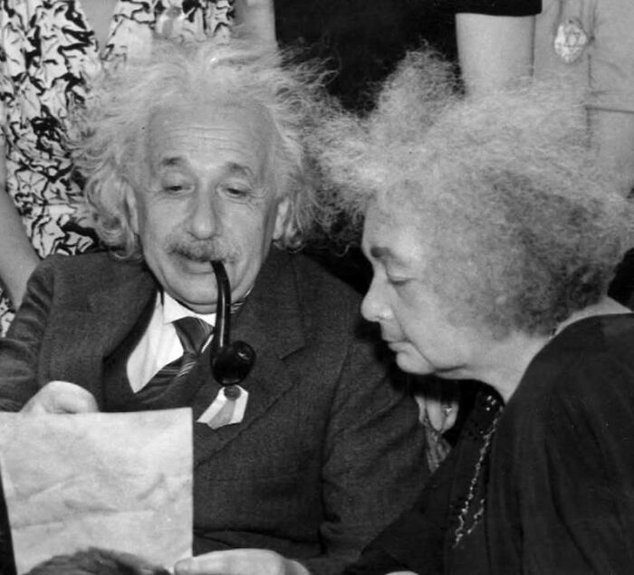 Dos personas históricas con cabello alborotado revisando un documento, mostrando un lado distinto de la historia.