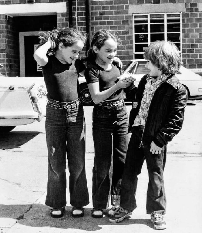Niños sonrientes interactuando en espacio urbano, foto en blanco y negro con ángulos alternativos únicos.
