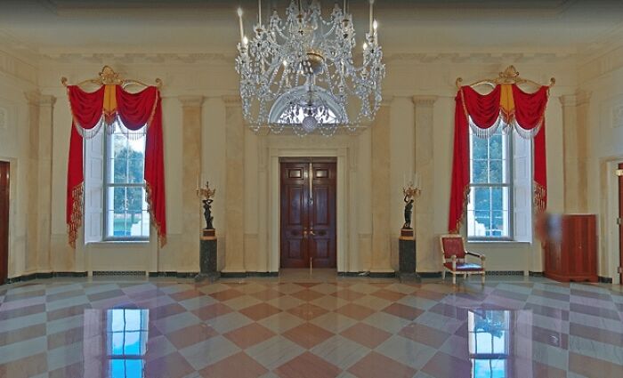Salón elegante con lámpara de araña y ventanas con cortinas rojas, mostrando ángulos alternativos de eventos y lugares.