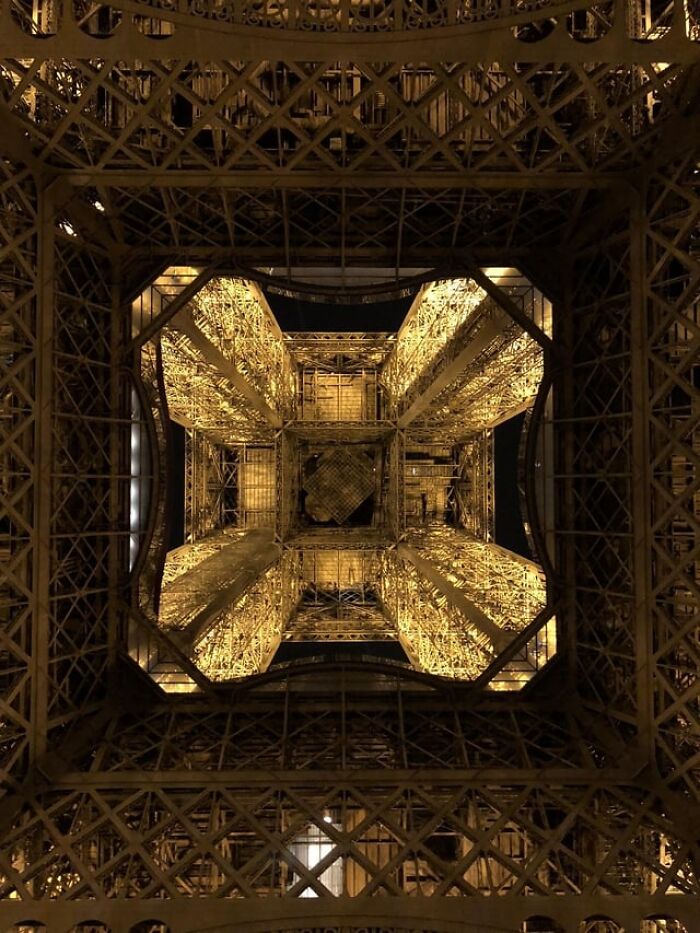 Vista desde abajo con ángulos alternativos de la estructura iluminada de la Torre Eiffel de noche.