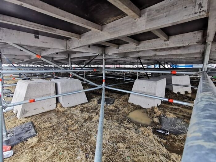 Estructura con ángulos alternativos de soporte en construcción vistos desde abajo en un sitio de tierra y metal.