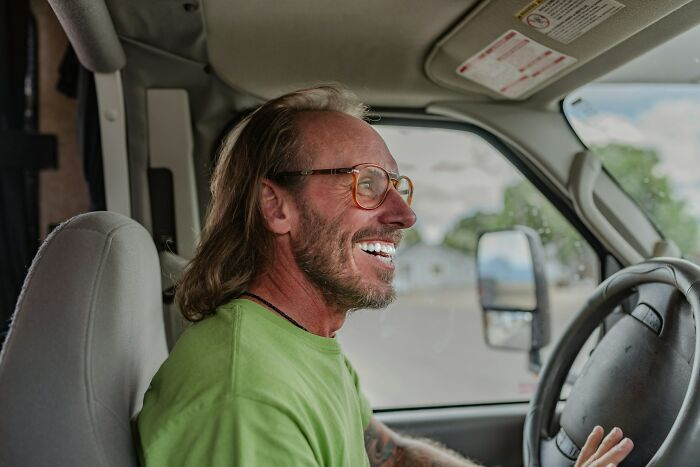 Hombre sonriente con gafas conduciendo vehículo, ilustrando momentos en que se intentó corregir a la persona equivocada.
