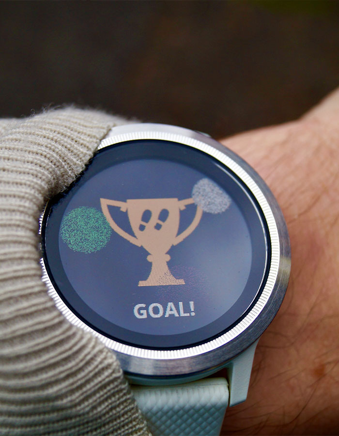 Pulsera inteligente mostrando trofeo y meta alcanzada, destacando la tendencia de caminar 30 minutos al estilo japonés.