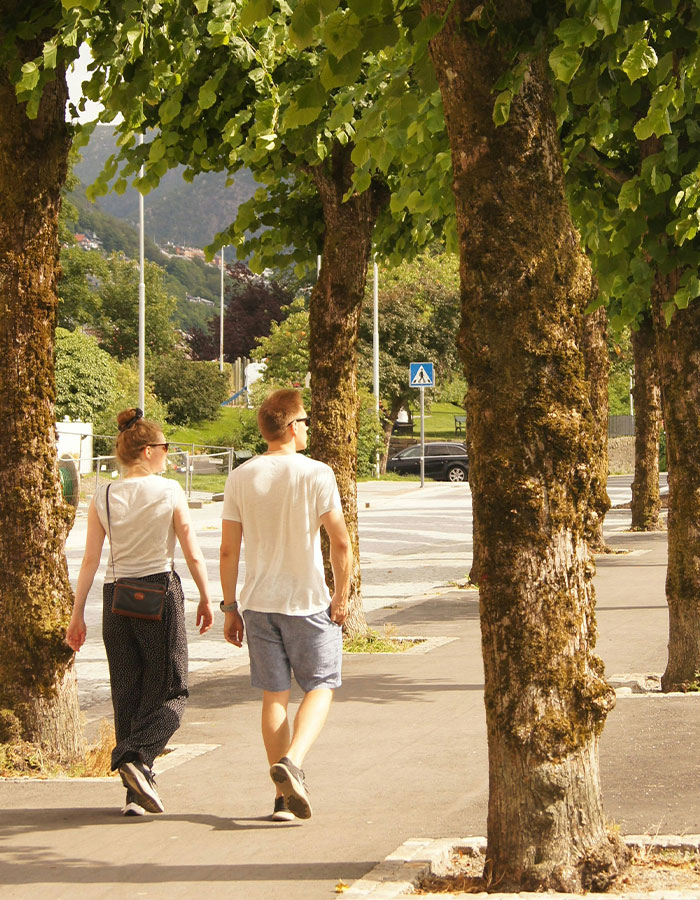 Hombre y mujer caminando por sendero arbolado, mostrando la tendencia japonesa de caminar 30 minutos como actividad saludable.