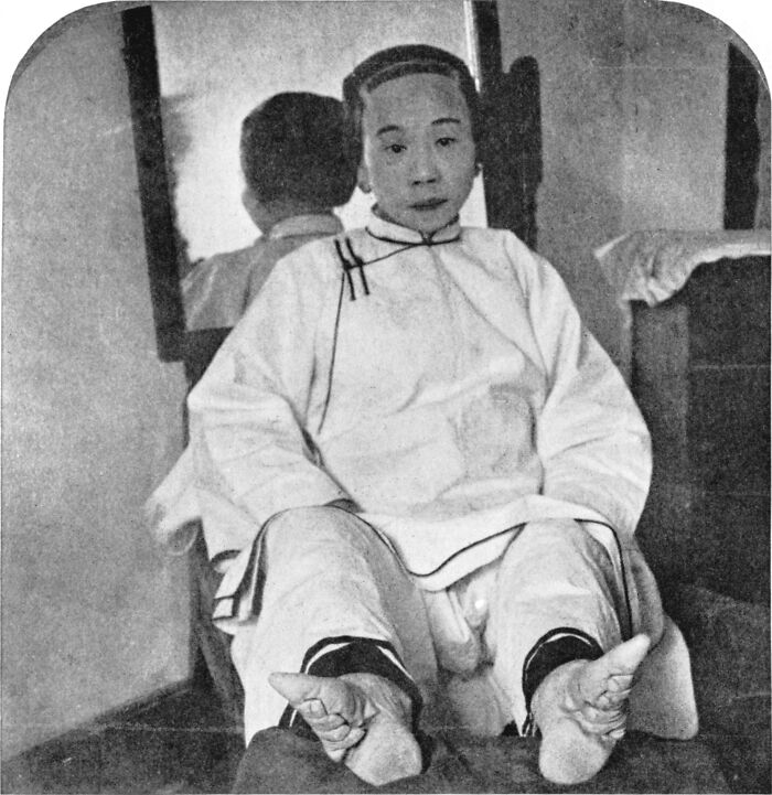 Hombre vestido con ropa tradicional en foto del pasado inquietante en blanco y negro, sentado frente a espejo.