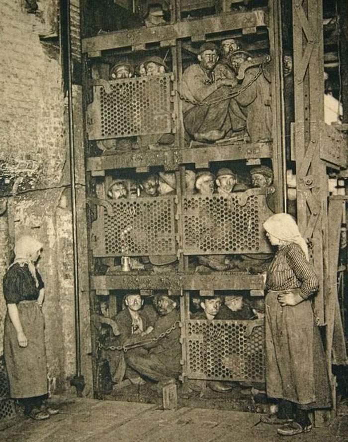 Hombres atrapados en jaulas de metal en una antigua prisión, imagen impactante y inquietante del pasado.