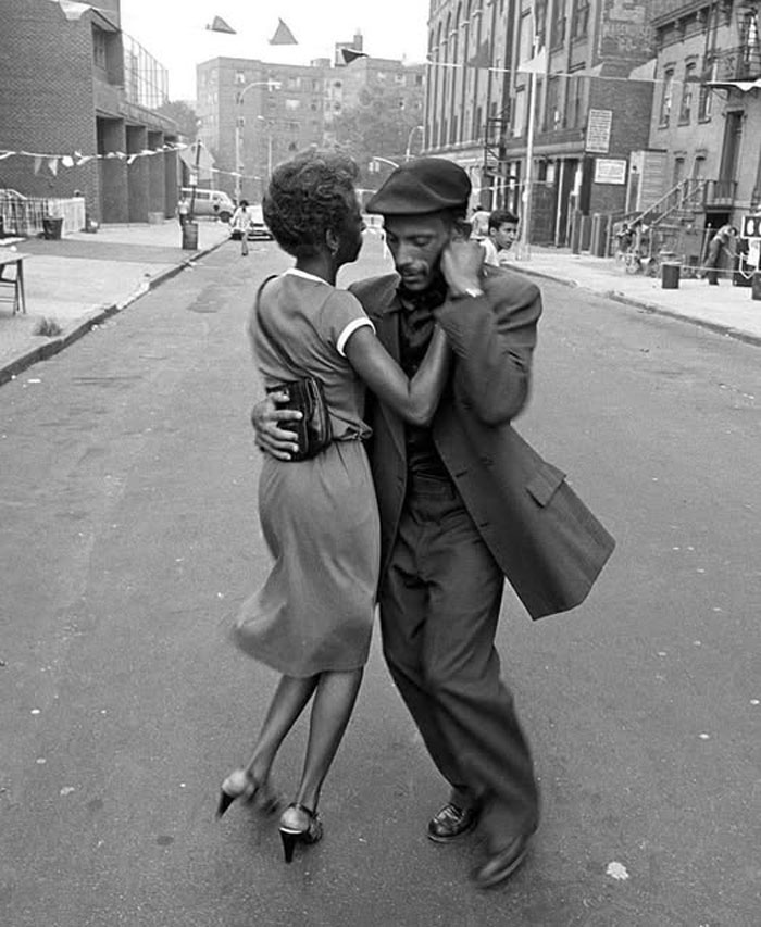 Pareja bailando en la calle, foto histórica en blanco y negro que muestra un momento de la vida urbana del pasado.