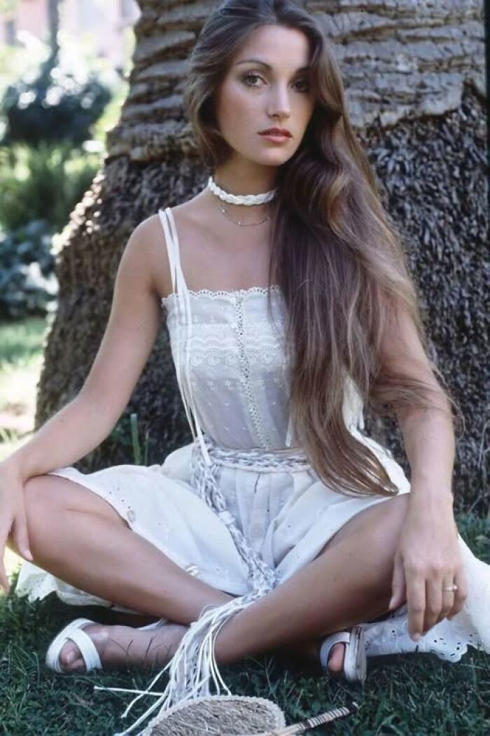 Joven con vestido blanco sentada en el césped frente a un árbol en una curiosa foto histórica del pasado inédito.