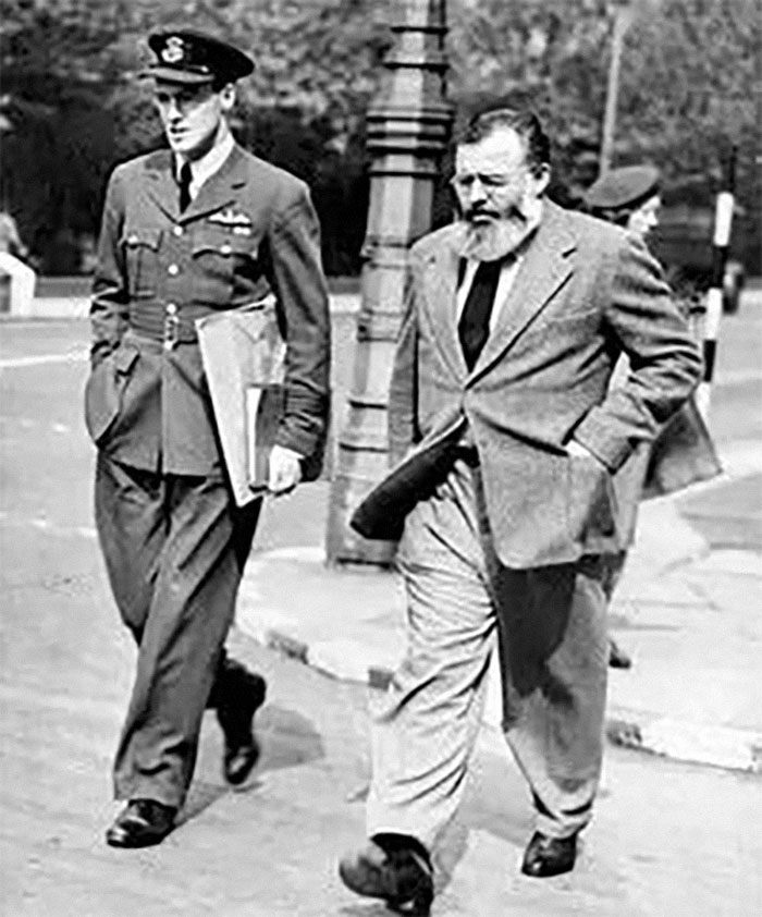 Hombre con uniforme militar y hombre con traje caminando en una calle, foto histórica curiosa del pasado inédito.
