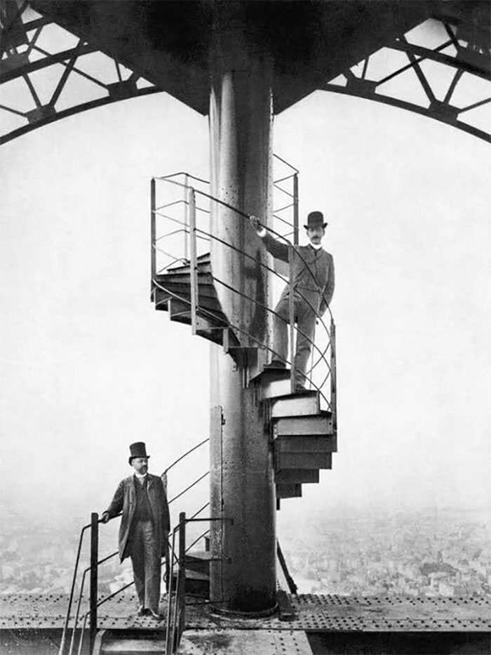 Hombres con sombreros de copa en escalera de caracol en estructura metálica, foto histórica curiosa del pasado inédito.