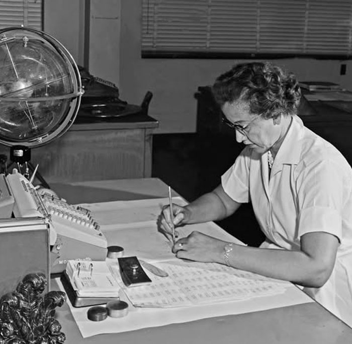 Mujer trabajando en oficina antigua con calculadora y documentos, foto histórica que refleja el pasado inédito del siglo XX.