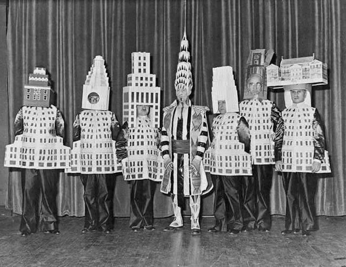 Personas con disfraces de edificios icónicos posando en foto histórica curiosa y única del pasado inédito.