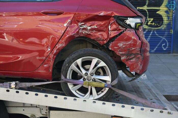 Auto rojo con daños severos en la parte trasera, ejemplo de historias terroríficas escuchadas sin querer en conversaciones privadas.