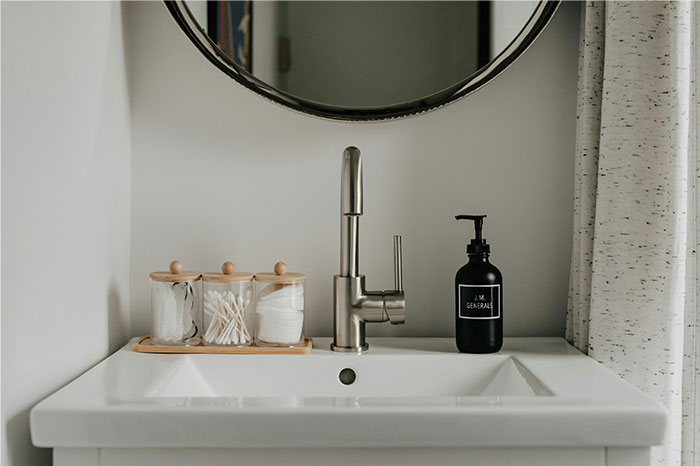 Lavabo moderno con espejo redondo y productos de higiene, imagen relacionada con mujeres y pérdida de atracción en pareja.