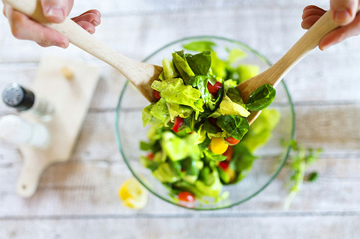 Manos mezclando una ensalada fresca, concepto visual de pérdida de atracción en pareja según mujeres.