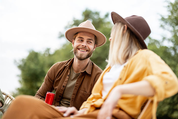 Pareja sonriente al aire libre, hombre y mujer con sombreros conversando, tema sobre pérdida de atracción en relaciones.