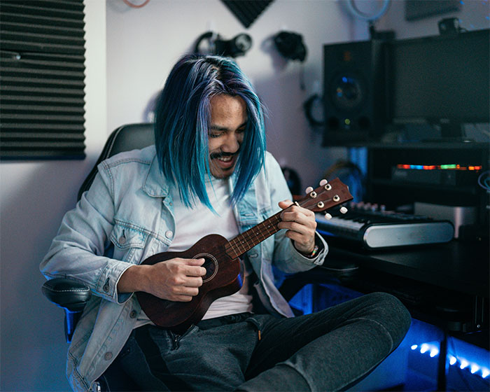 Hombre joven tocando ukelele en estudio de música, ilustrando momento de pérdida de atracción en pareja según mujeres.