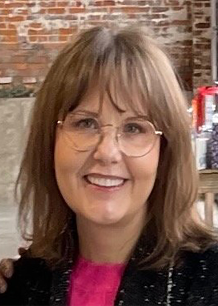Mujer sonriente tras lifting facial, con gafas y cabello castaño a la altura de los hombros, en un ambiente casual.