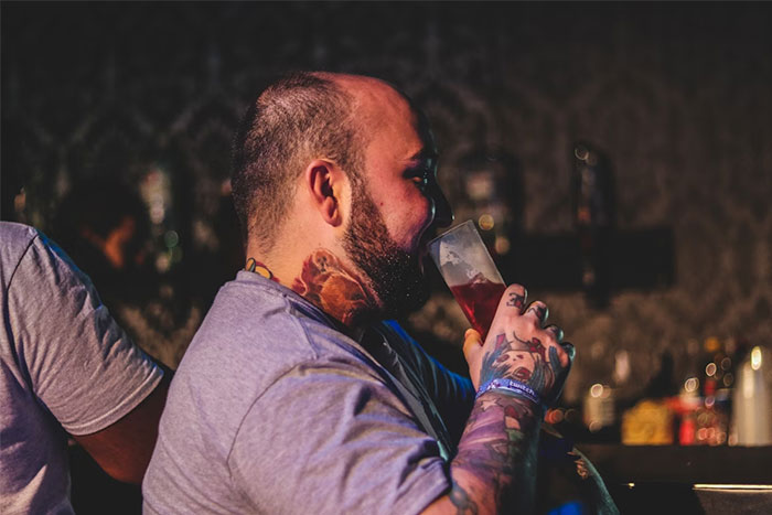 Hombre con tatuajes bebiendo en un bar, escenario típico en citas terribles presenciadas por camareros.
