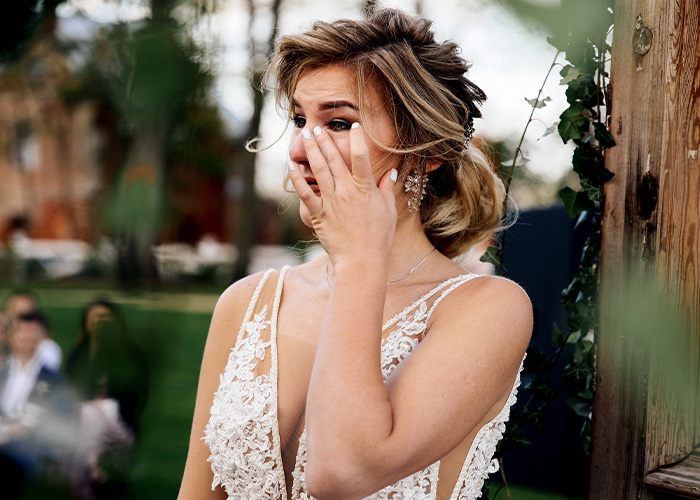 Mujer con vestido de novia con expresión emotiva, ilustrando momentos difíciles que se soportan con las suegras.