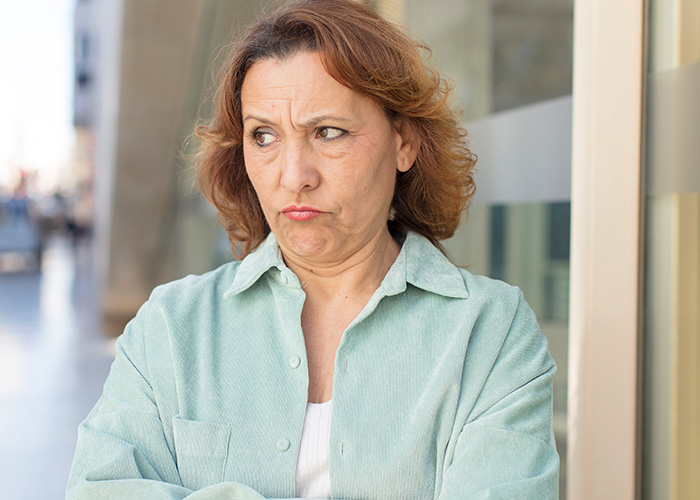 Mujer con expresión disgustada reflejando situaciones difíciles que tienen que soportar con sus suegras en la convivencia diaria.