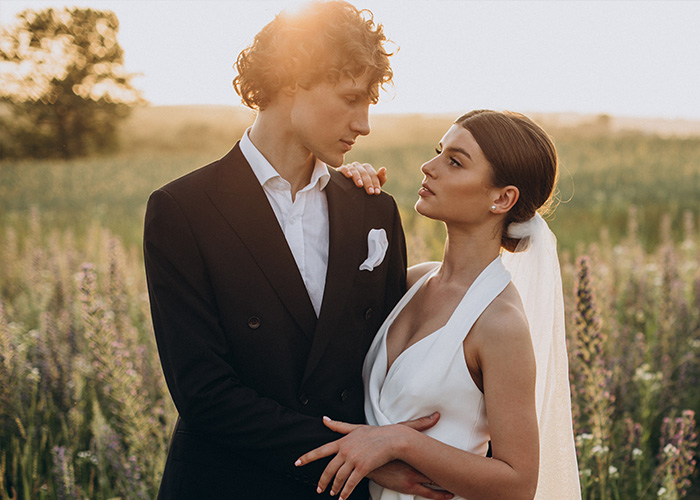 Pareja de recién casados en un campo al atardecer, símbolo de relaciones y lo que deben soportar con sus suegras.
