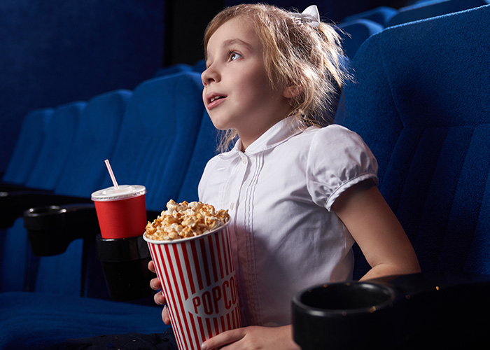 Niña en cine con palomitas y bebida, representando personas que tuvieron desagradables presentimientos y su realidad.