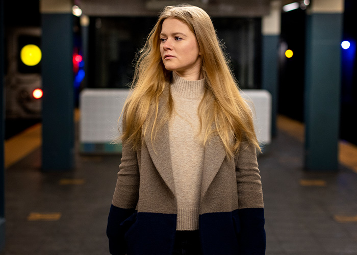 Mujer con presentimiento desagradable en estación de metro poco iluminada mirando hacia un lado con expresión seria.